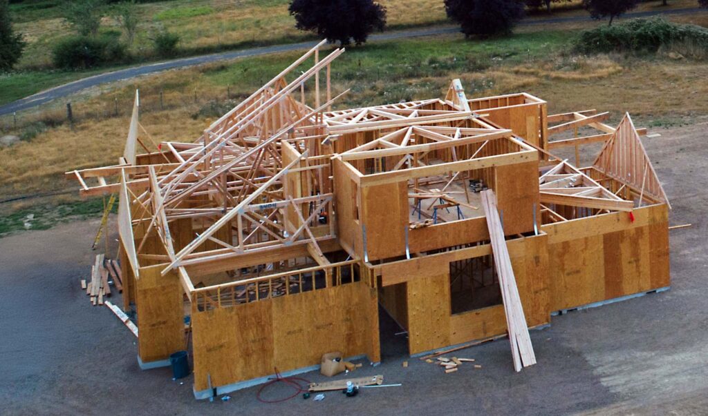 Structural engineering construction - house under construction showing strucutral engineering framing and roof members being installed